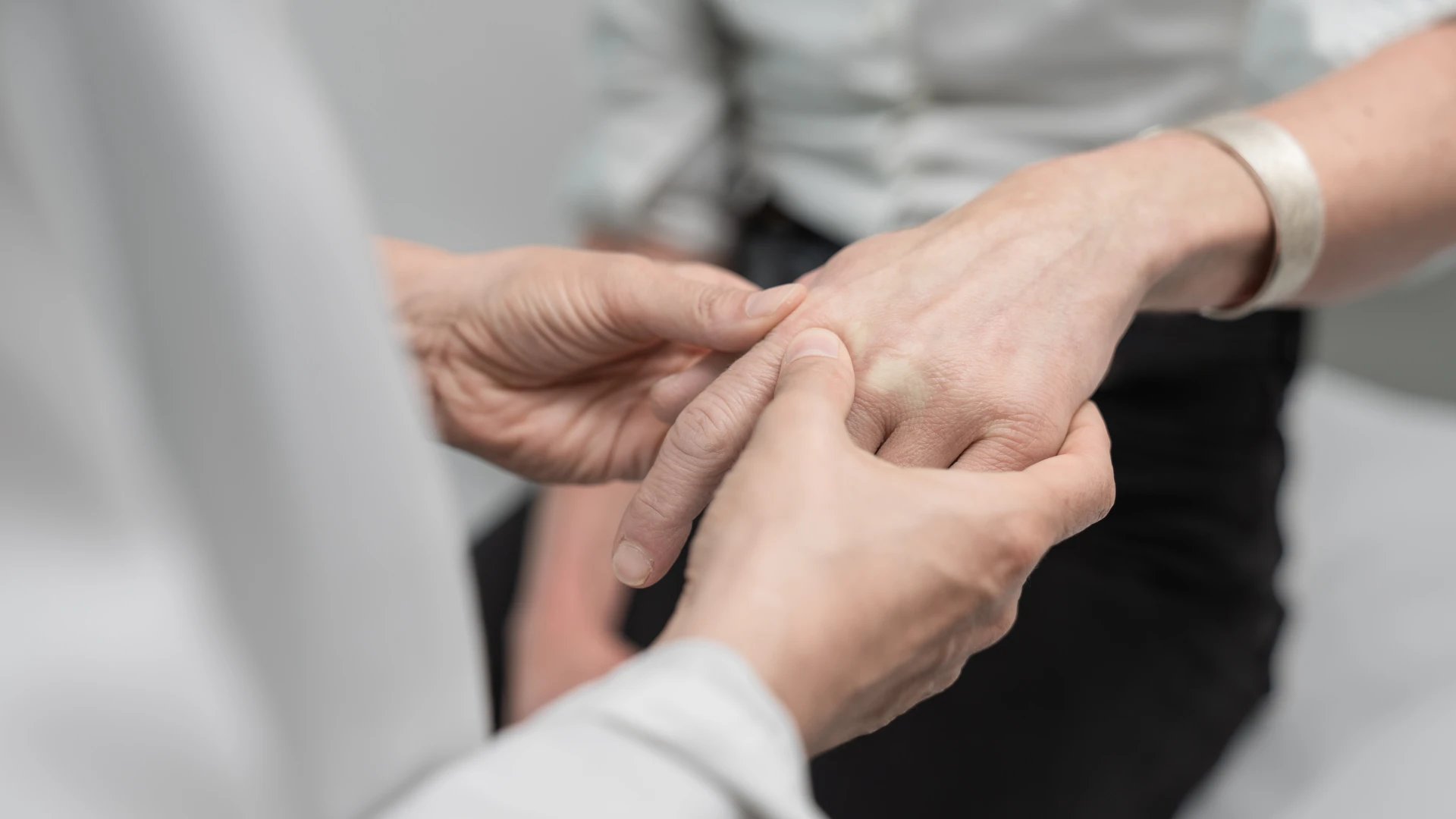 Arzt untersucht Fingergelenke einer RA-Patientin