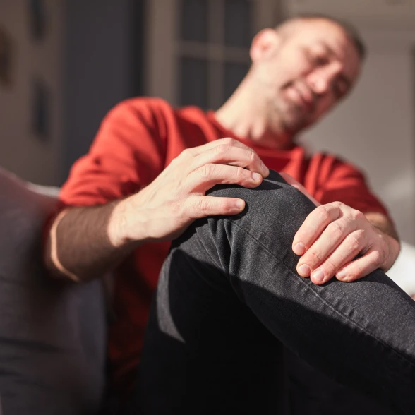 Mann fasst sich an schmerzendes Knie