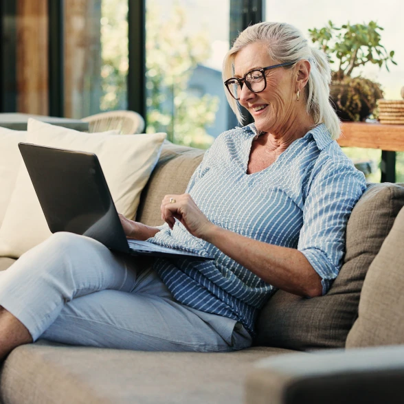 Seniorin sucht Information und Beratung Seniorin daheim auf dem Sofa, arbeitet am Laptop