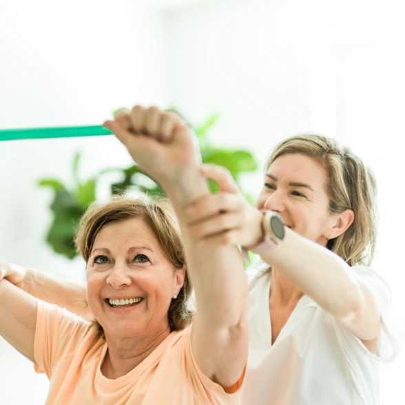 Physiotherapie Physiotherapeutin zeigt Patientin Übung.