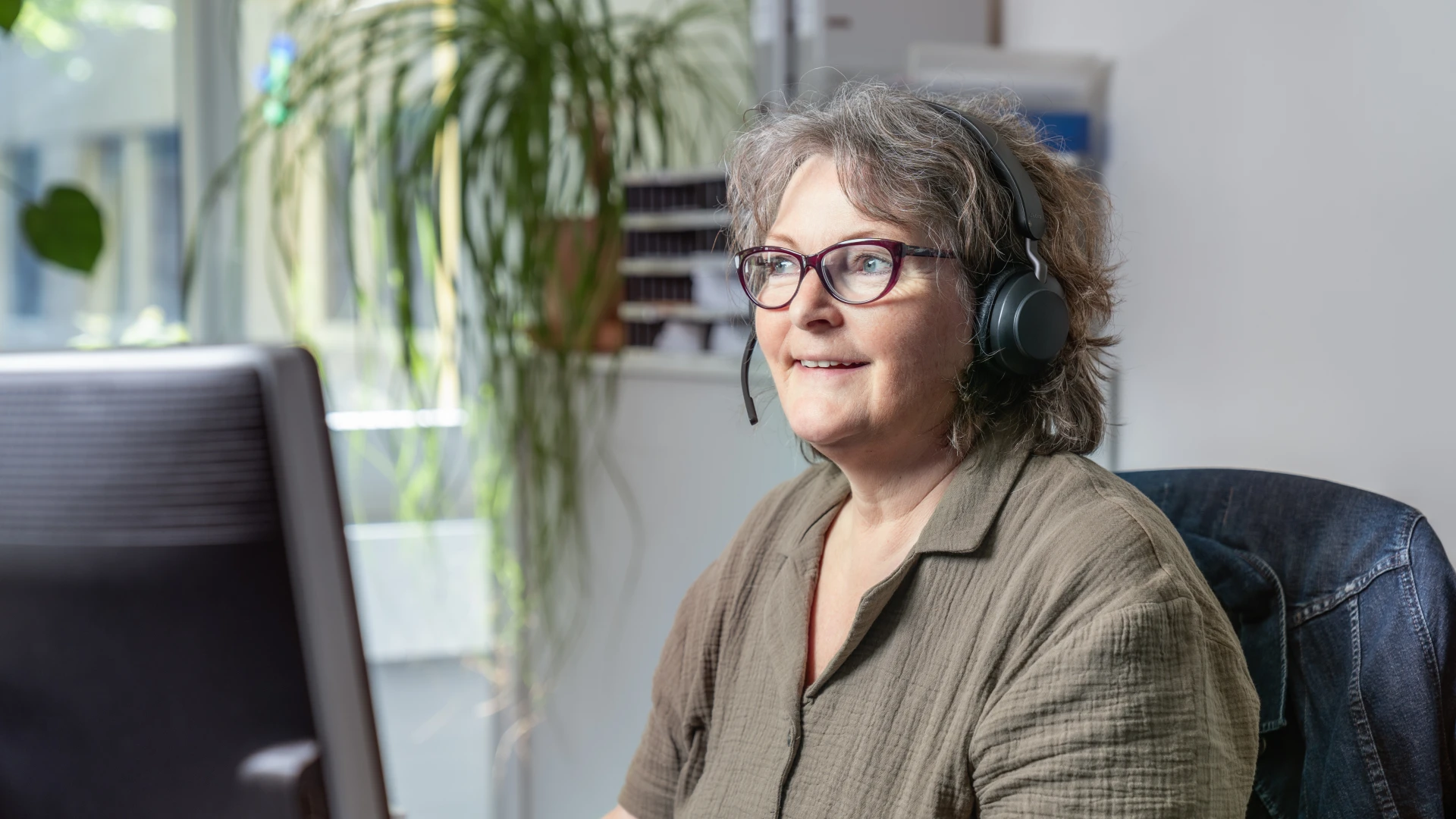 Frau mit Headset am Schreibtisch