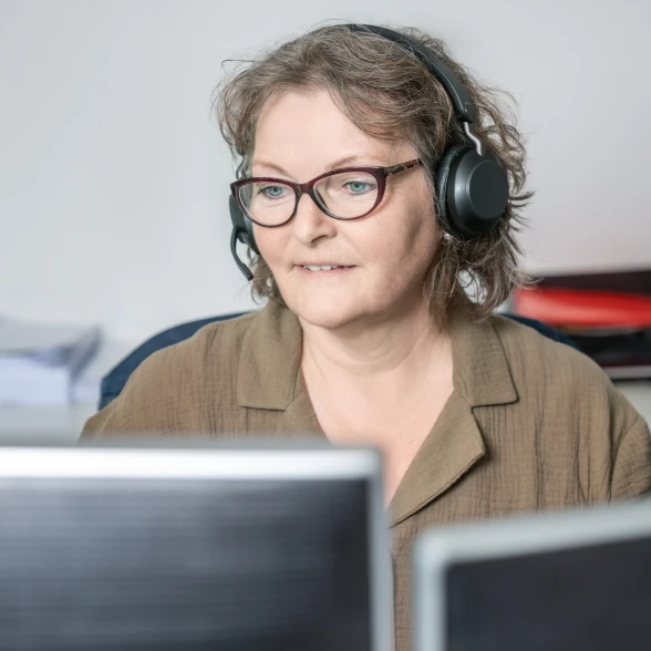 Beraterin mit Telefonkopfhörer vor ihren Bildschirmen