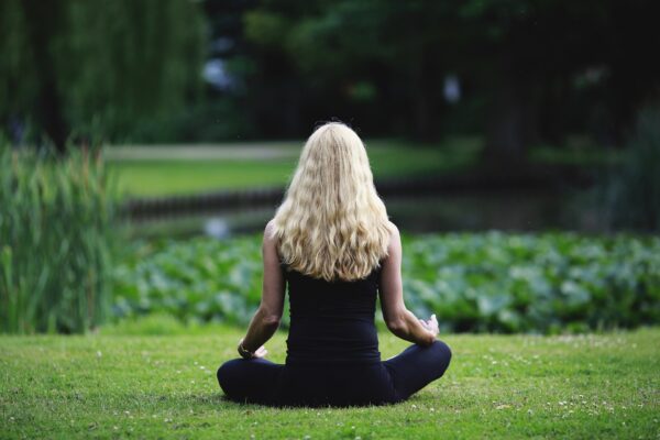 Frau im Schneidersitz meditierend im Park