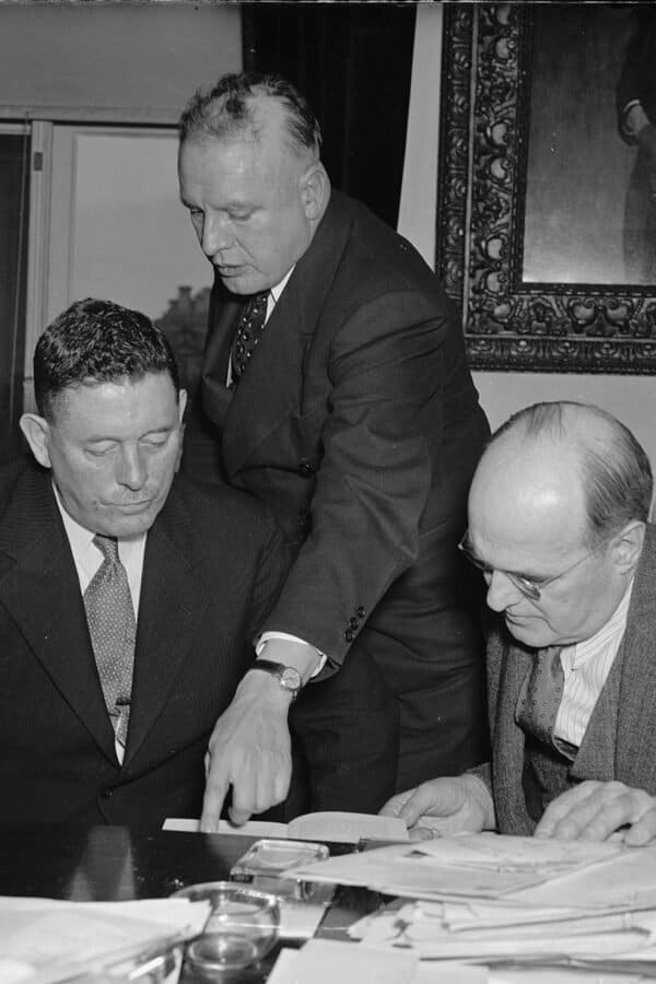 In the photograph, left to right: Col. C.H.L. Sharman, Chief of Canadian Narcotic Control; Harry Anslinger, U.S. Commissioner of Narcotics; and Assistant Secretary of Treasury Stephen B. Gibbons